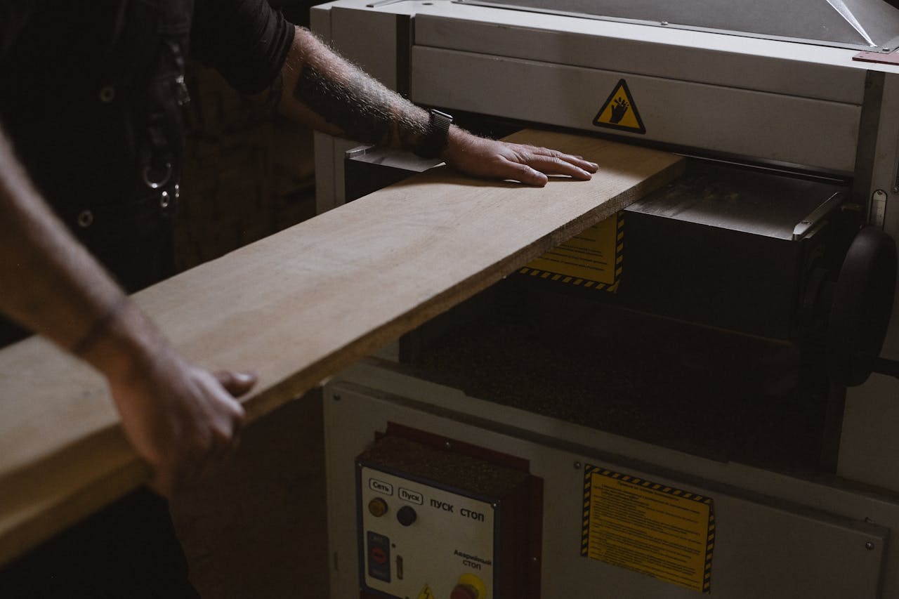 Crop carpenter using  thicknessing machine to trim wooden board