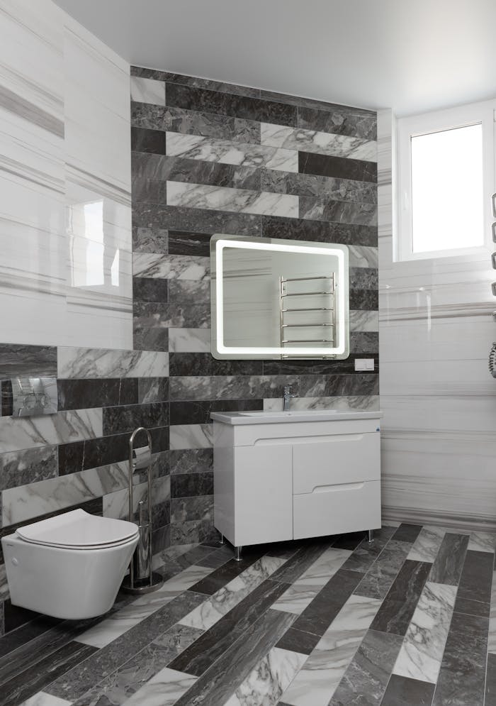 Creative design of bathroom with toilet bowl against white washstand under mirror reflecting rack in light house